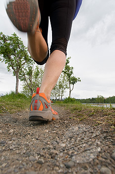 Closeup of a trail runners feet running on a gravel trail